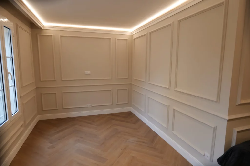 Murs à moulures et parquet posé en bâtons rompus dans le séjour rénové